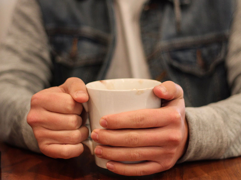 Person holding a cup containing a hot drink
