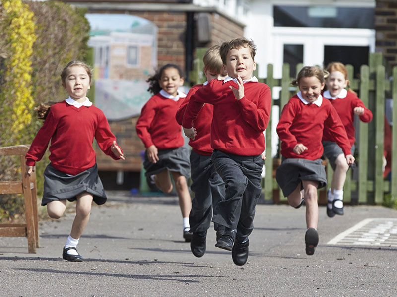 Happy school children running in a playground
