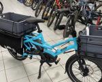 image of an electric cargo bike colour light blue with carrying boxes front and rear