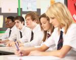 five teenagers wearing school uniform working at a desk