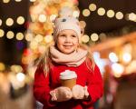 A girl in a red coat with Christmas lights in the background