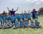 Happy children pictured with cricket coaches in a playing field