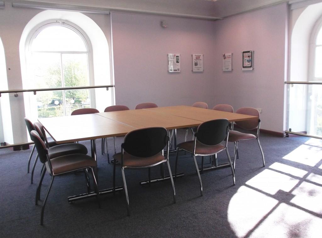 An interior meeting room with pink chairs set up around a large table.