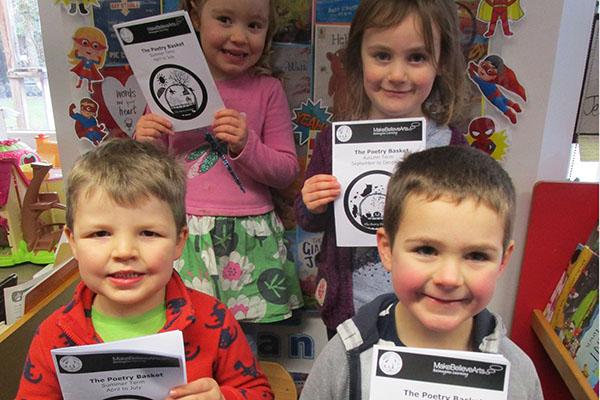 children holding pieces of card with poems written on them