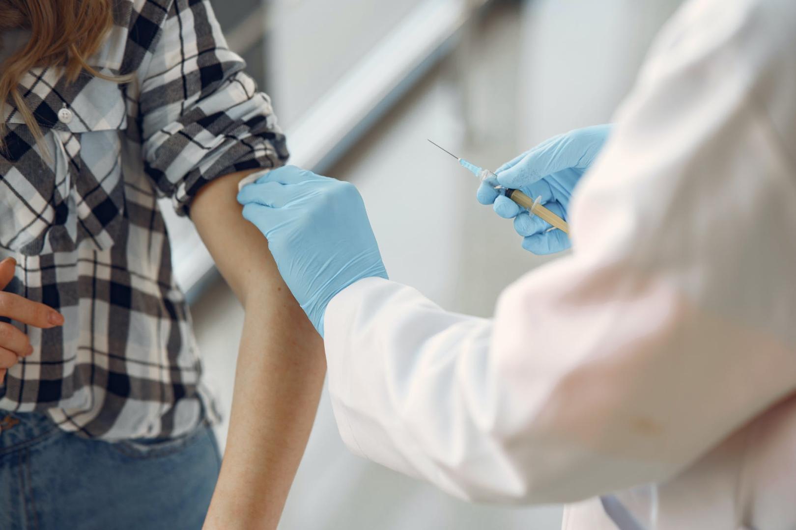 medical professional administering a vaccination into patient's arm via a syringe