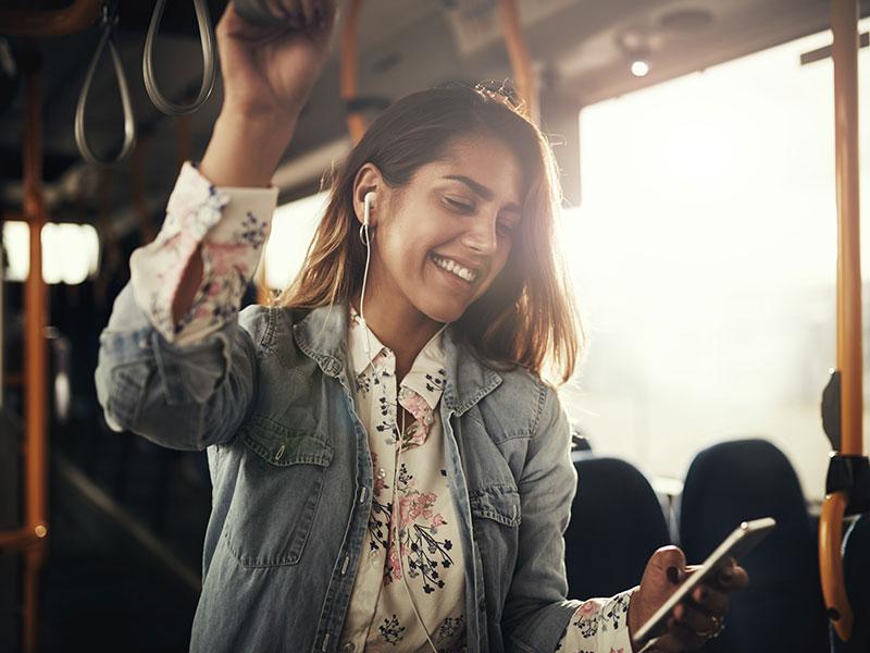 smiling lady on a bus holding onto an overhead handle