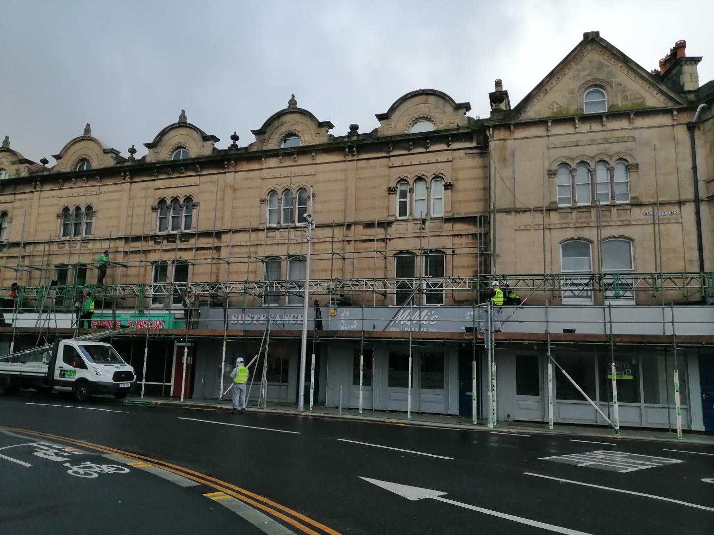 A row of shops with scaffolding outside the front of the buildings.