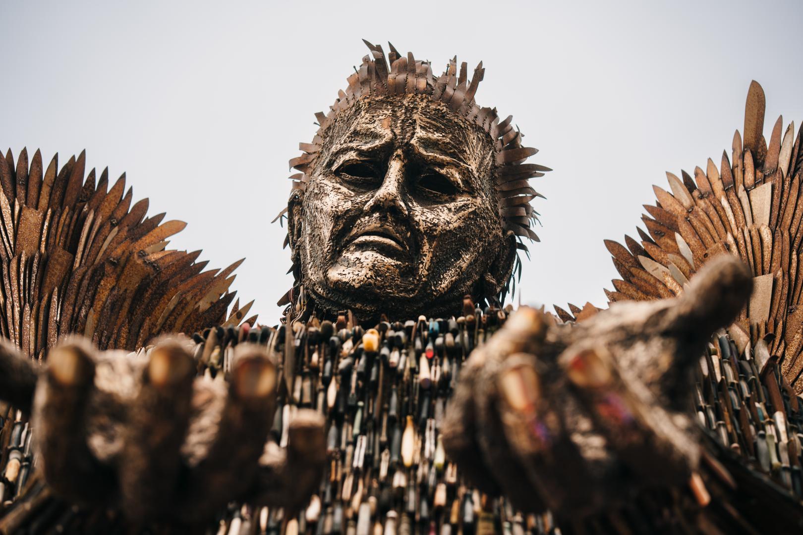 The Knife Angel shot from the ground, with its hands outstretched towards the camera. 