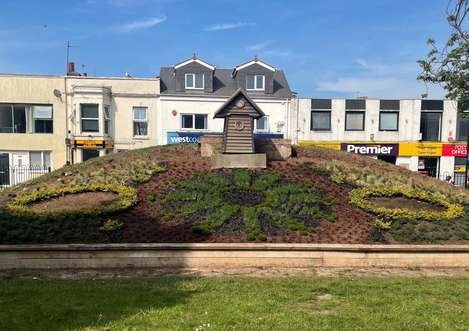 The finished floral clock in Weston-super-Mare. Ornamental shrubs are planted like the face of a clock, and there are two circles on either side. 