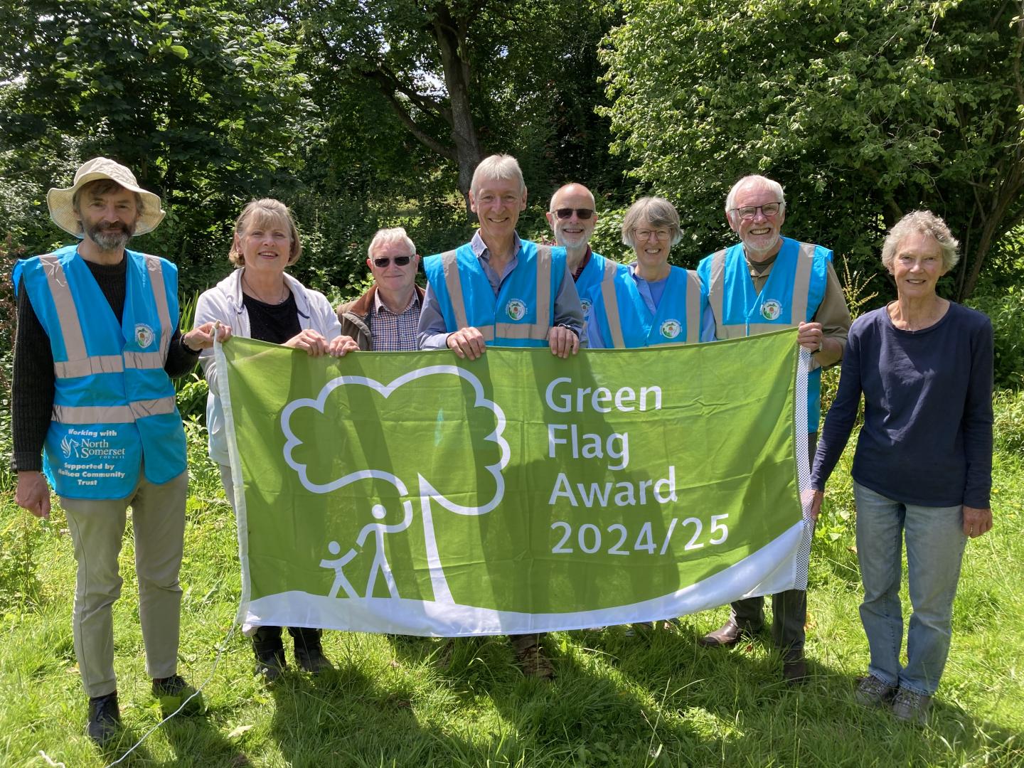 A group of volunteers stand in a park holding up their Green Flag