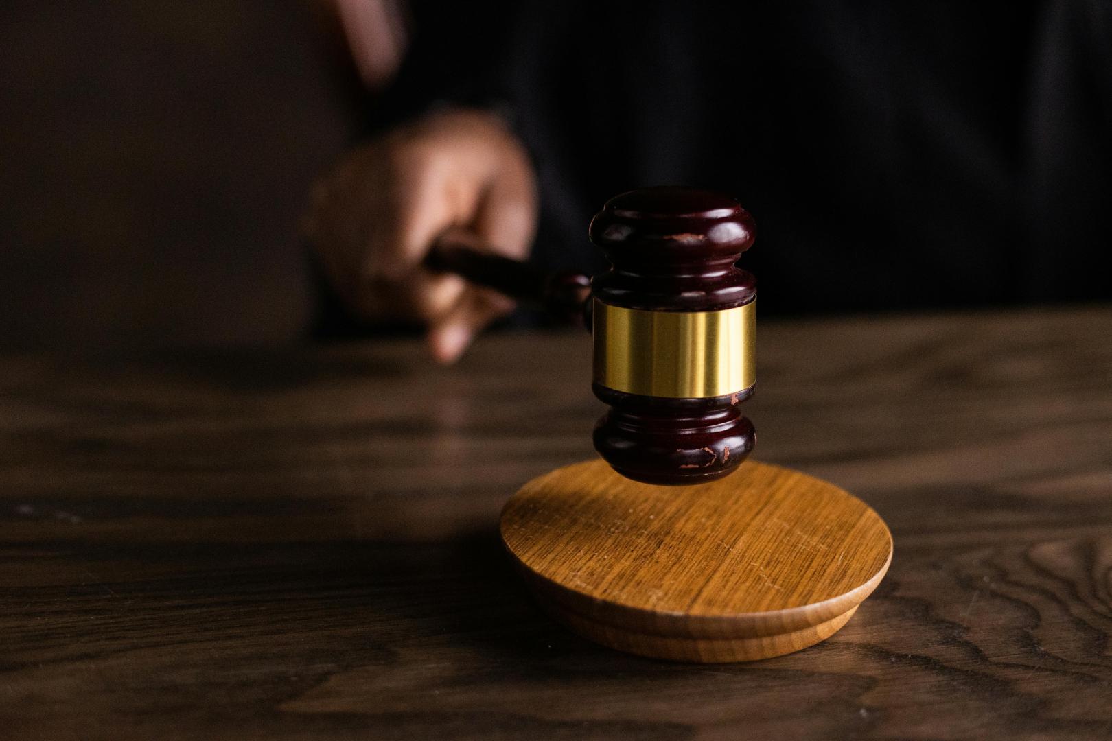 A gavel hits a base on a dark wood table