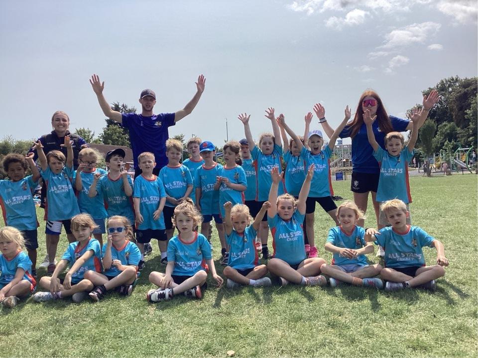 Happy children pictured with cricket coaches in a playing field