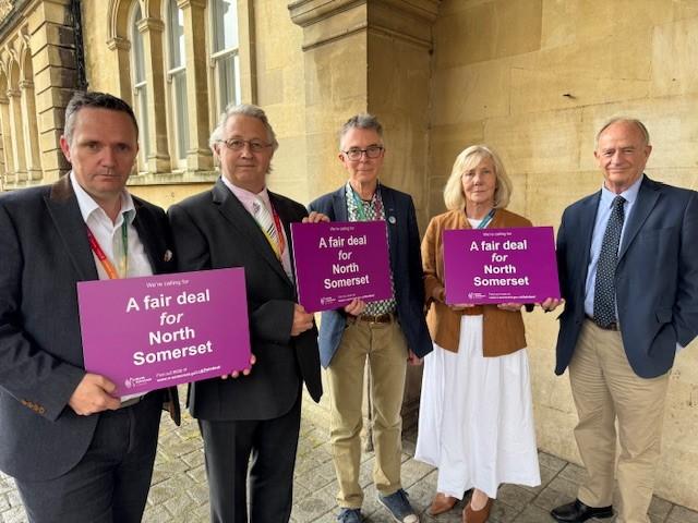 Group leaders stood holding Fair Deal for North Somerset signs