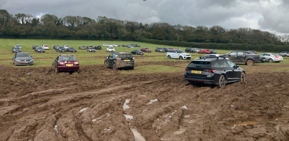 cars parked erratically in extremely muddy field 