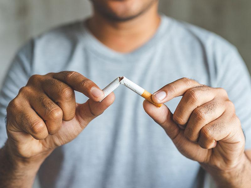 A man snapping an unlit cigarette in half
