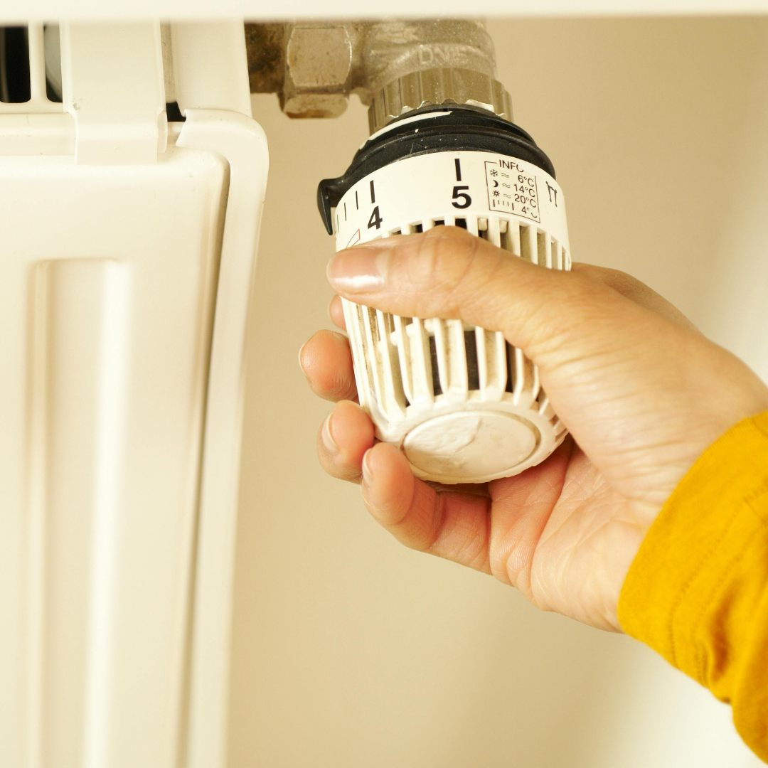 Hand turning up a radiator temperature dial