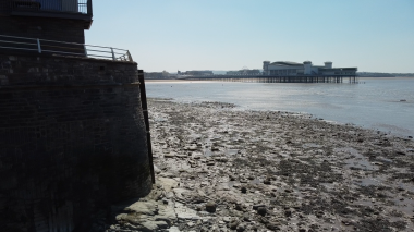 The Grand Pier is in the distance, with exposed mud flats and rocks in the mid ground