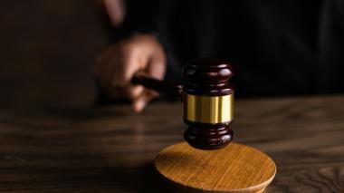 A gavel hits a base on a dark wood table