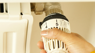 Hand turning up a radiator temperature dial